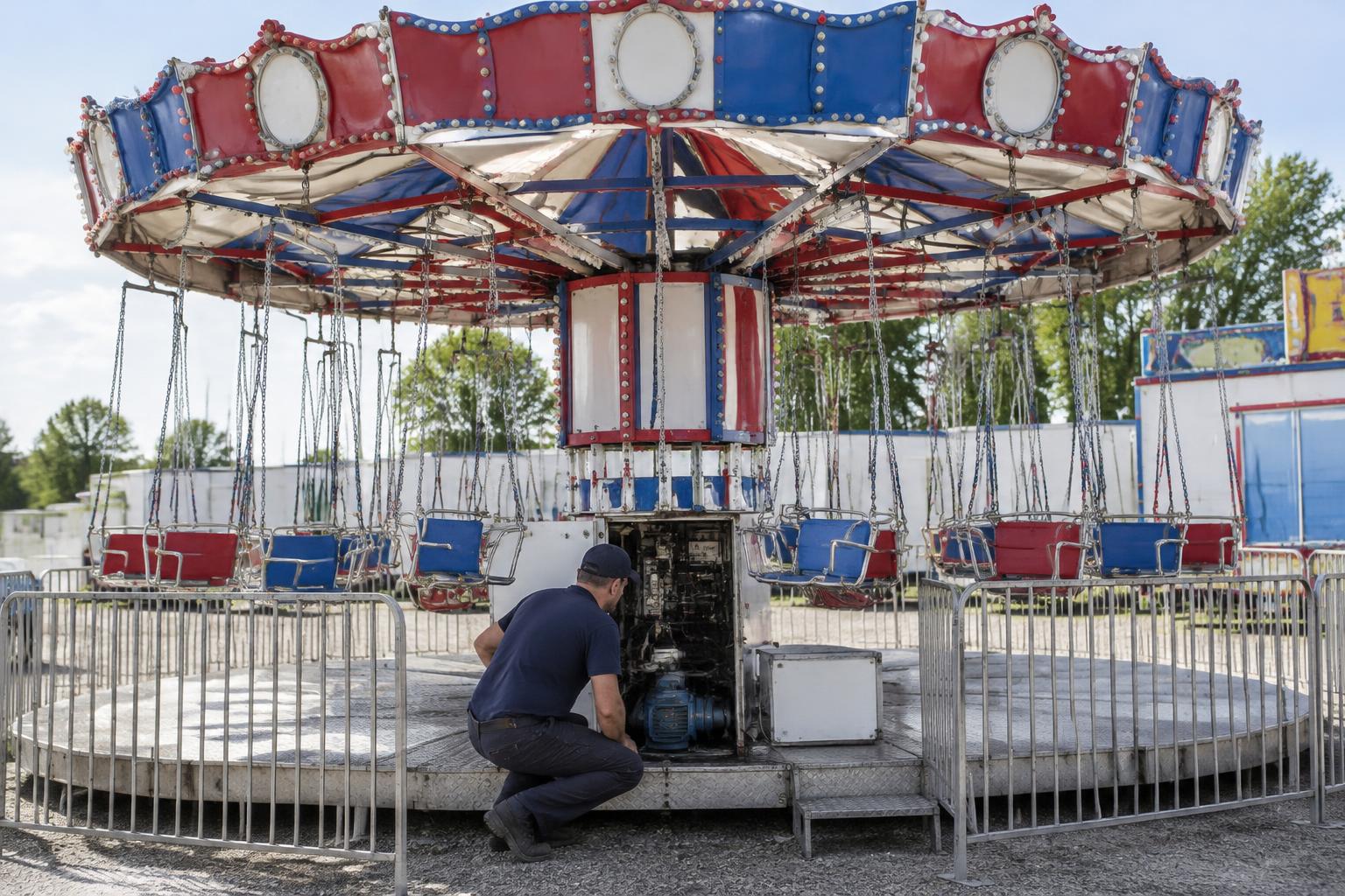 Technicien devant le mécanisme ouvert d’un manège à chaînes immobilisé et sans public